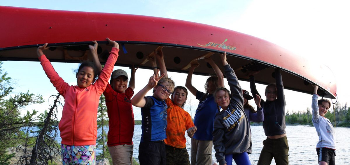 kids lifting up a red canoe