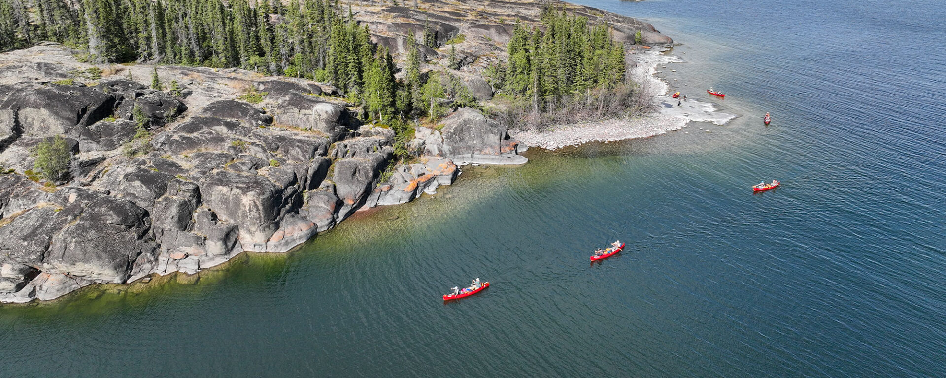 canoes paddling on rocky shore on great slave lake