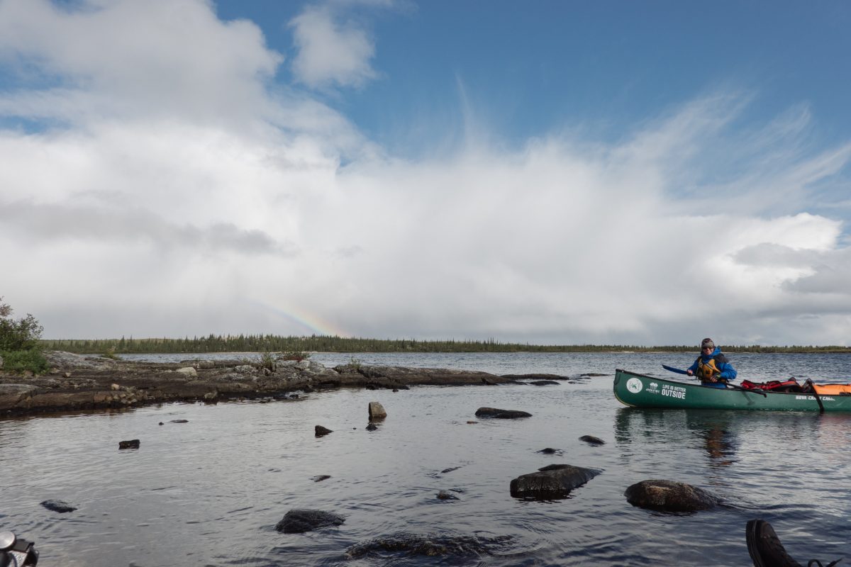 paddling in the arctic with a cloud and a rainbow