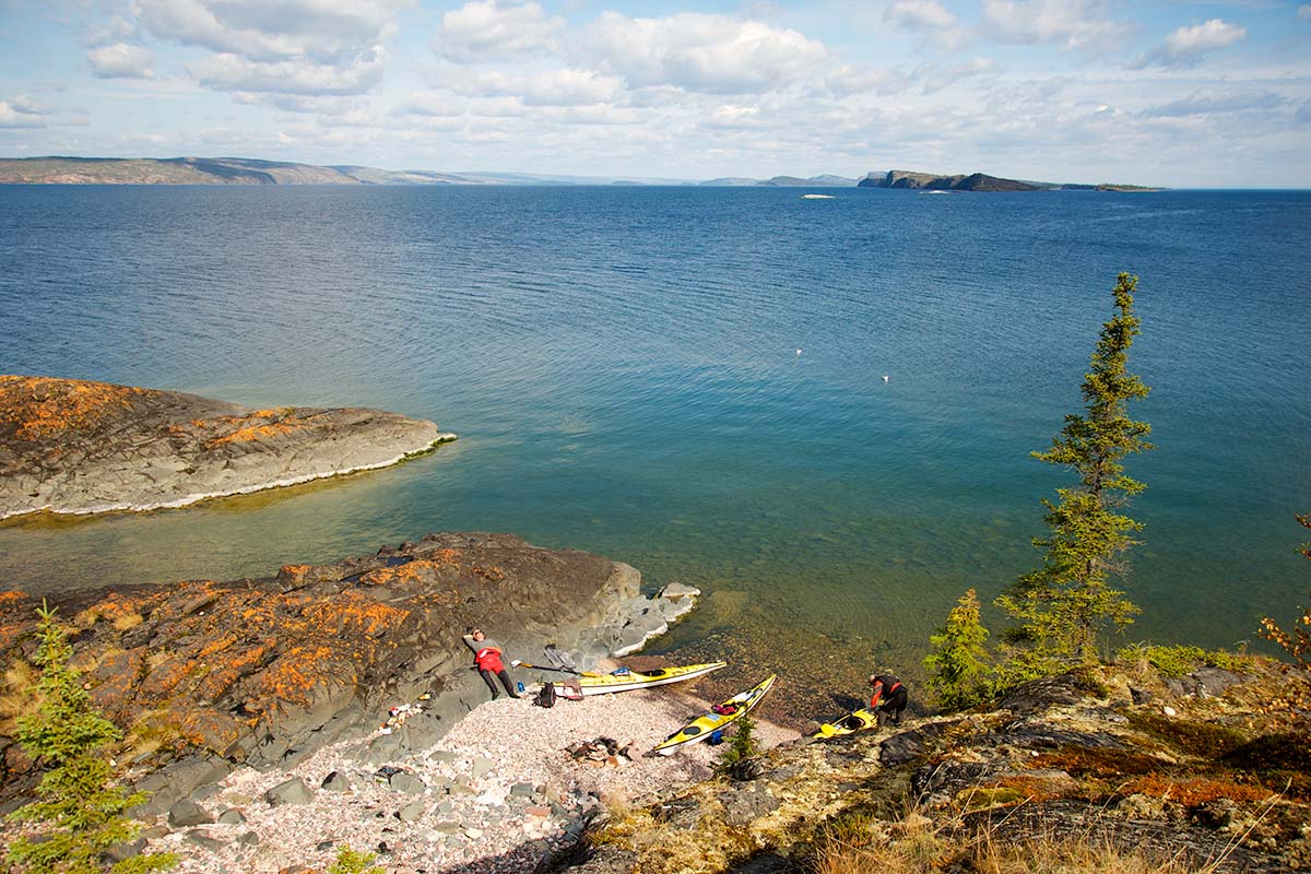 kayakers on the shore of great slave lake on a kayak trip in canada