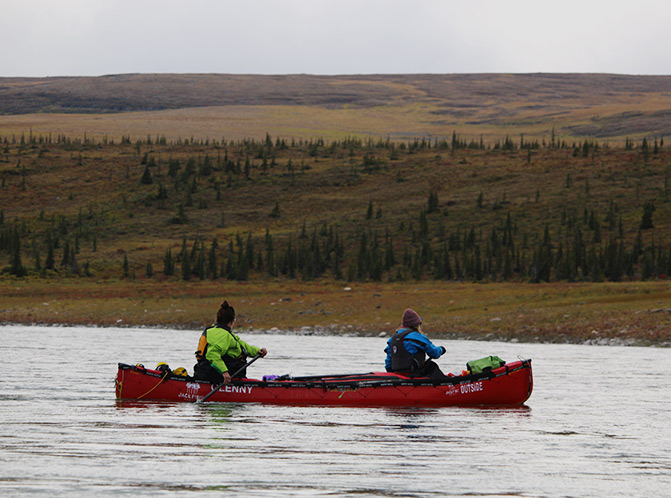 two paddlers look at rolling tundra hills